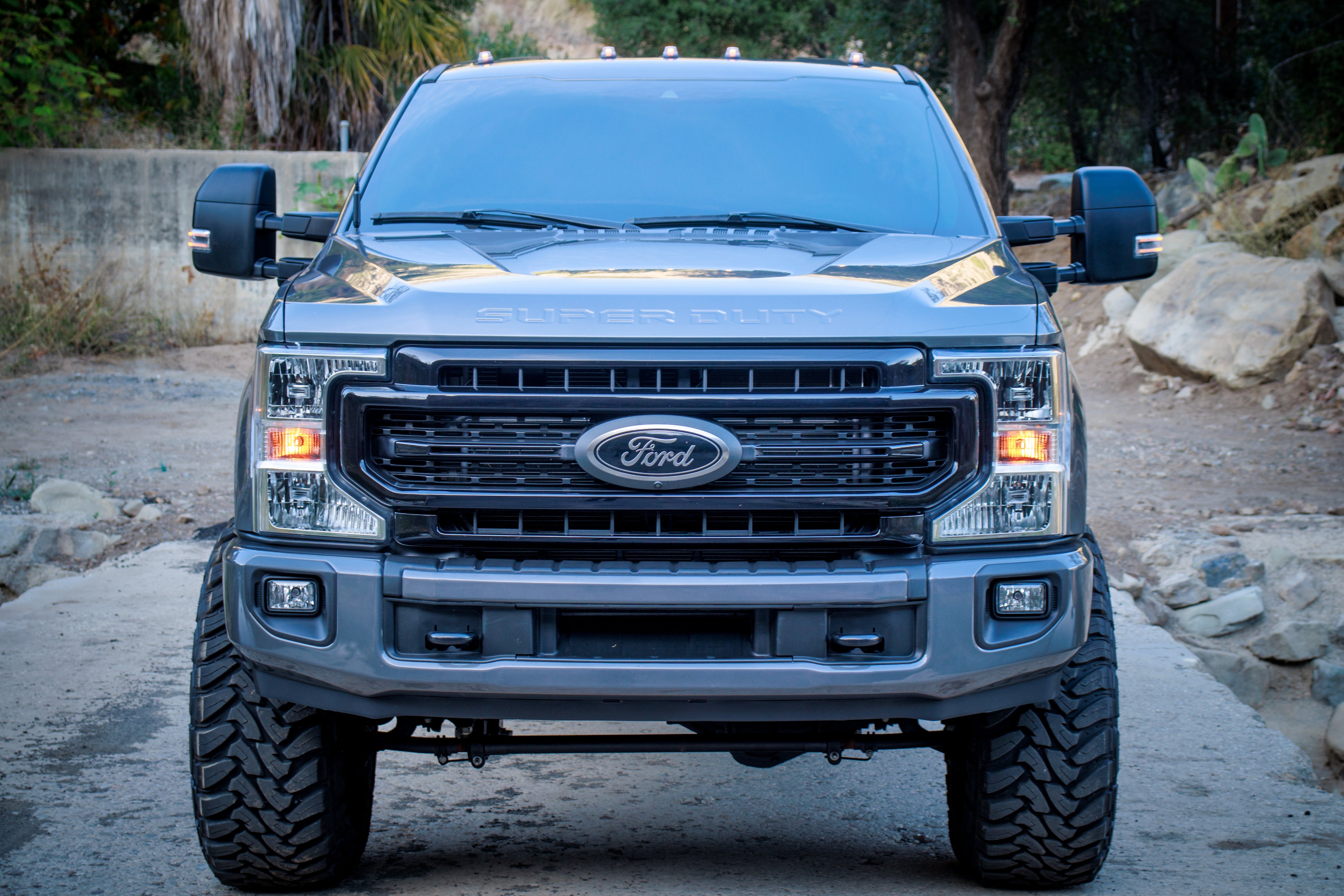Ford truck parked on a dirt road with rocks and trees in the background